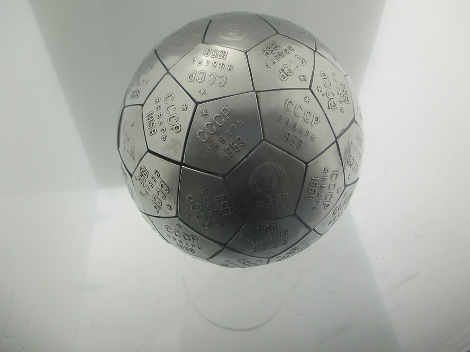 The copy of the Soviet pennant sent on the Luna 2 probe to the moon, at the Kansas Cosmosphere. The inscriptions (in Cyrillic script) say СССР Январь 1959 (USSR January 1959), shown together with the five-pointed star (Red Star, historical symbol of communism) and the coat of arms of the Soviet Union. Patrick Pelletier, CC BY-SA 3.0 , via Wikimedia Commons