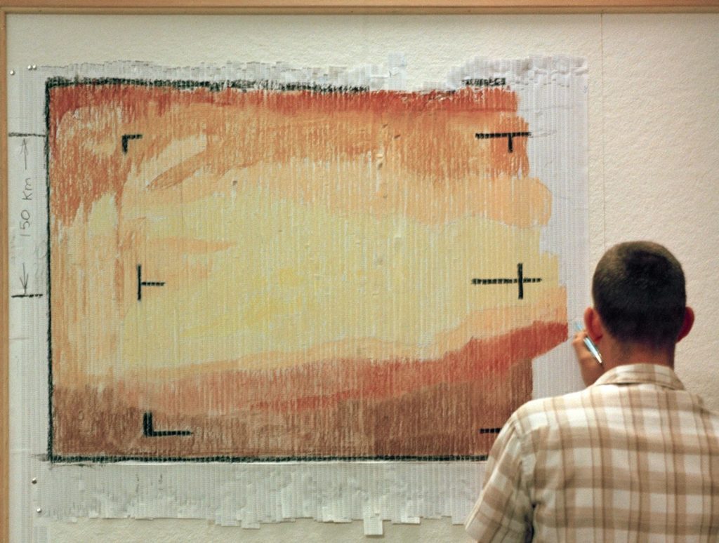 A "real-time data translator" machine converted Mariner 4 digital image data into numbers printed on paper. Too anxious to wait for the official processed image, employees from the Telecommunications Section cut the printout into strips, attached these strips side-by-side to a display panel, and hand colored the numbers like a paint-by-numbers picture. Credit: NASA/Jet Propulsion Laboratory-Caltech